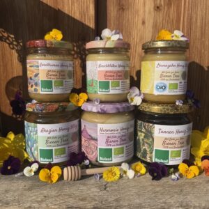 Drei Gläser des Gourmet Honig Pakets von Bienen Trax (Kornblumen, Kirschblüten, Löwenzahn Honig) mit Blüten dekoriert