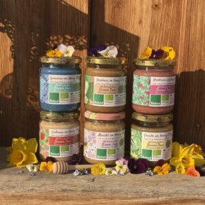 Drei Gläser Bunte Honigaufstriche von Bienen Trax (Spirulina, Haselnuss, Himbeere im Honig) mit Blüten dekoriert