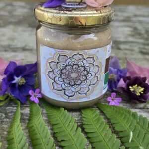 Glas Zimt im Honig von Bienen Trax, Nahaufnahme mit goldenem Deckel und lila sowie rosa Blüten