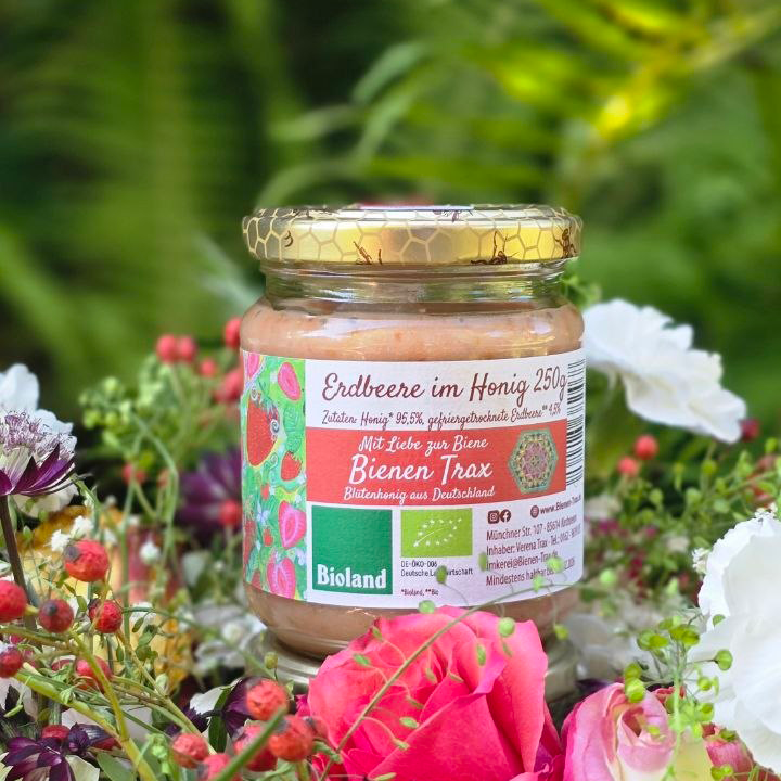 Glas Erdbeere im Honig 250g von Bienen Trax im Garten zwischen Blüten und Erdbeeren mit Bioland-Siegel